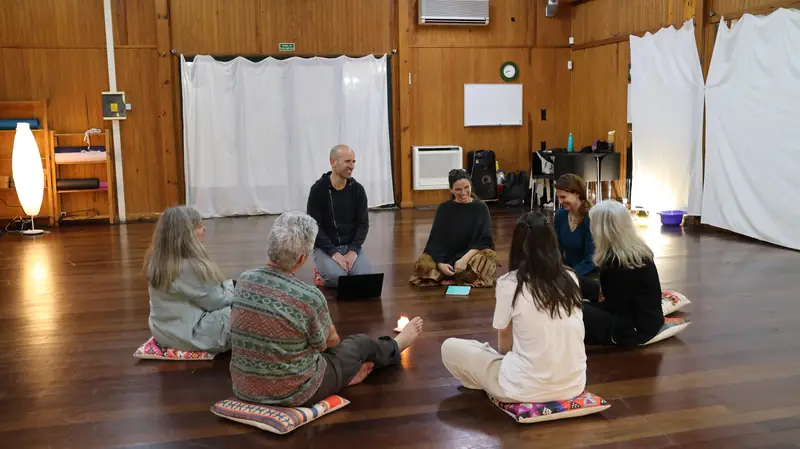 Grupo sentado em roda, à luz de velas, no início de uma aula